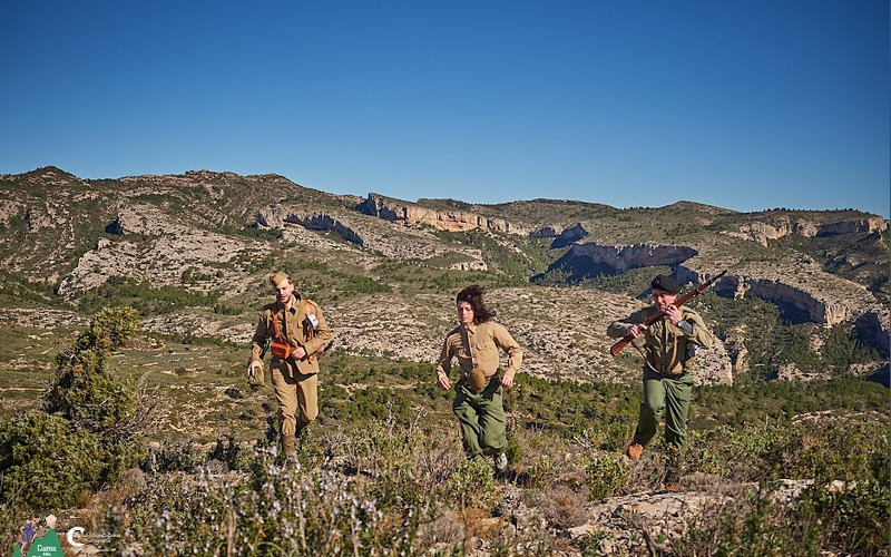 2 nois i una noia corrents per la muntanya vestits de soldats