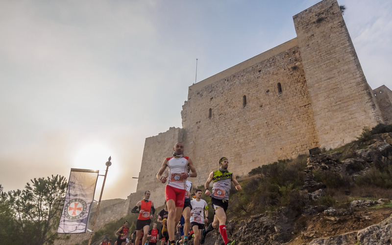 esportistes corrents devant del castell de Miravet