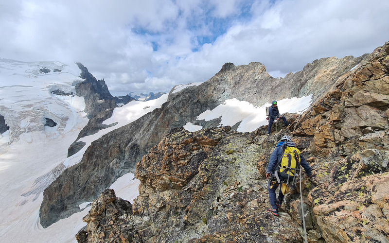 Dos persones fent alpinisme per la cresta de muntanyes mig nevades