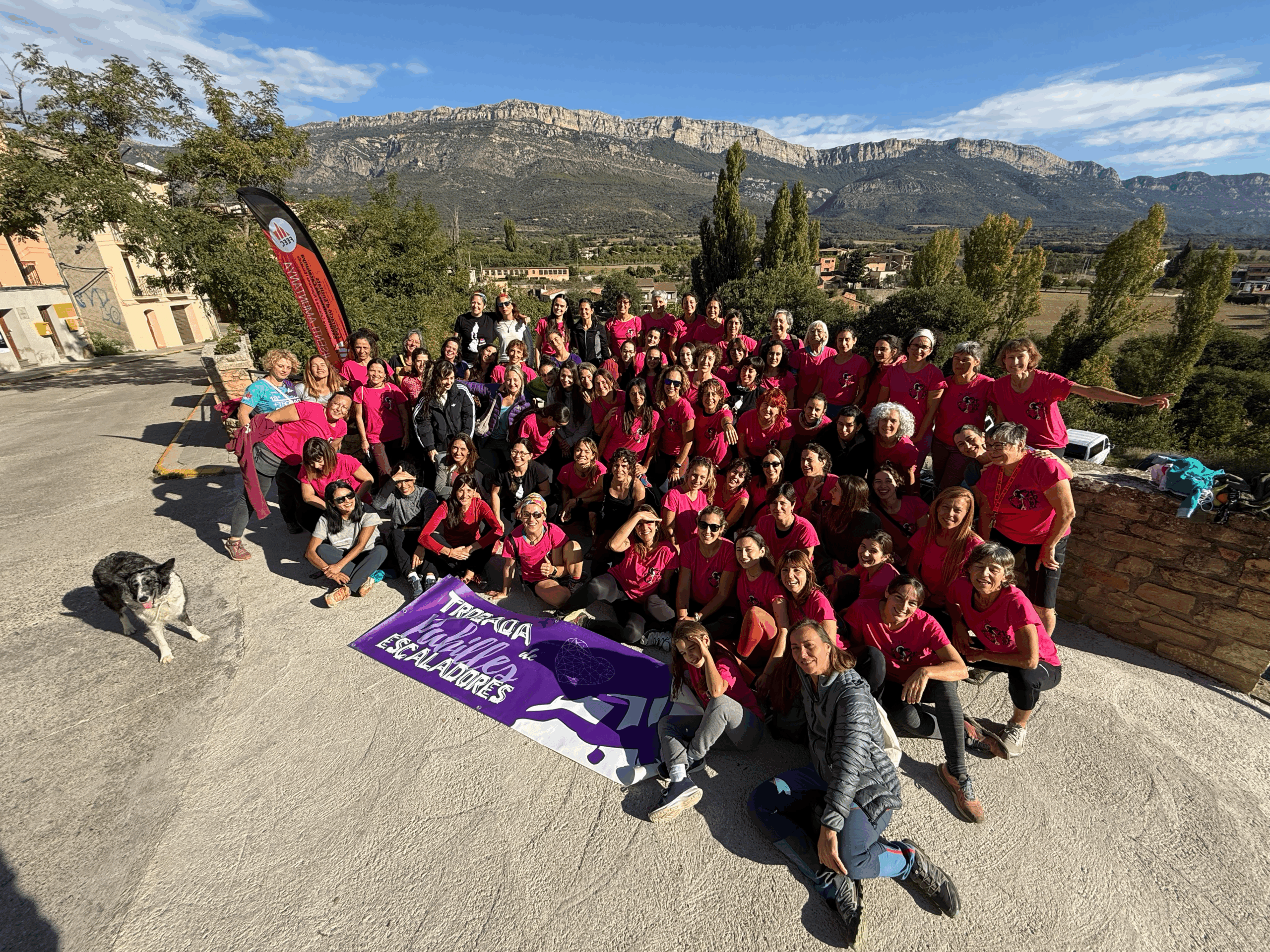 totes les pubilles escaladores juntes darrere de la seva pancarta lila i un gos border colly a l'esquerra